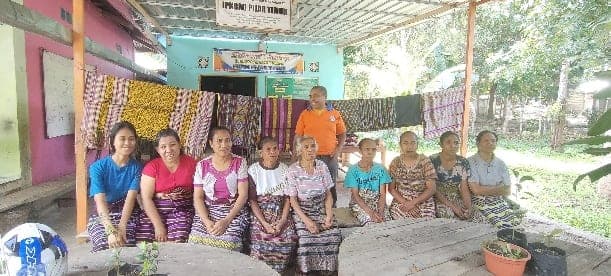Warga belajar berfoto bersama di depan kain tenun hasil karya mereka